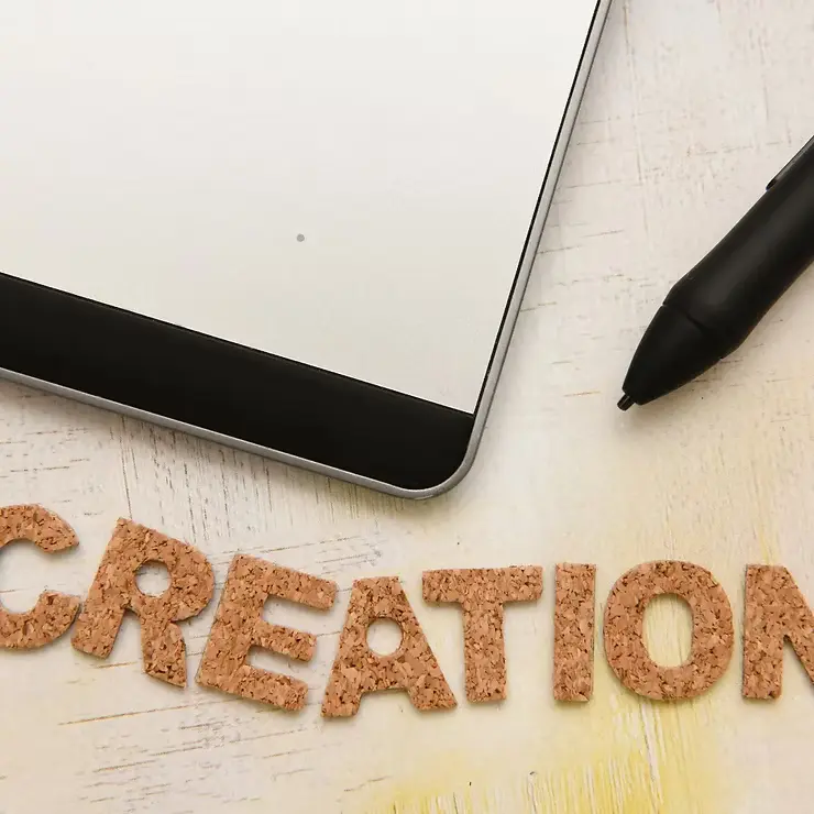 Tablet and stylus next to CREATION text – representing AI writing tools